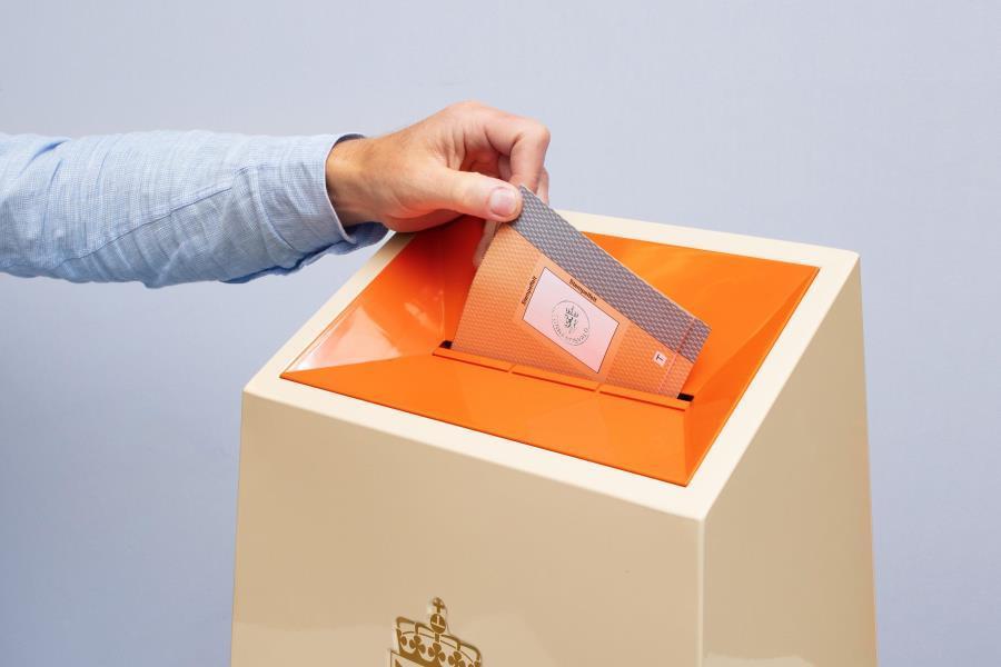 En hånd som slipper ned en stemmeseddel i en valgurne