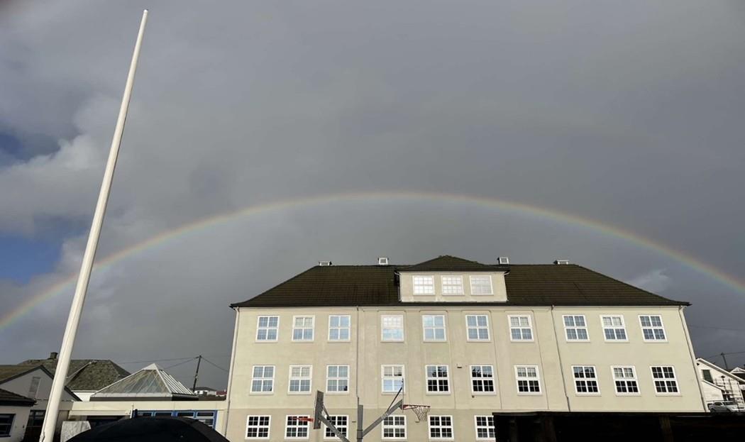 Skolebygget med en regnbue som går over bygget - Klikk for stort bilde